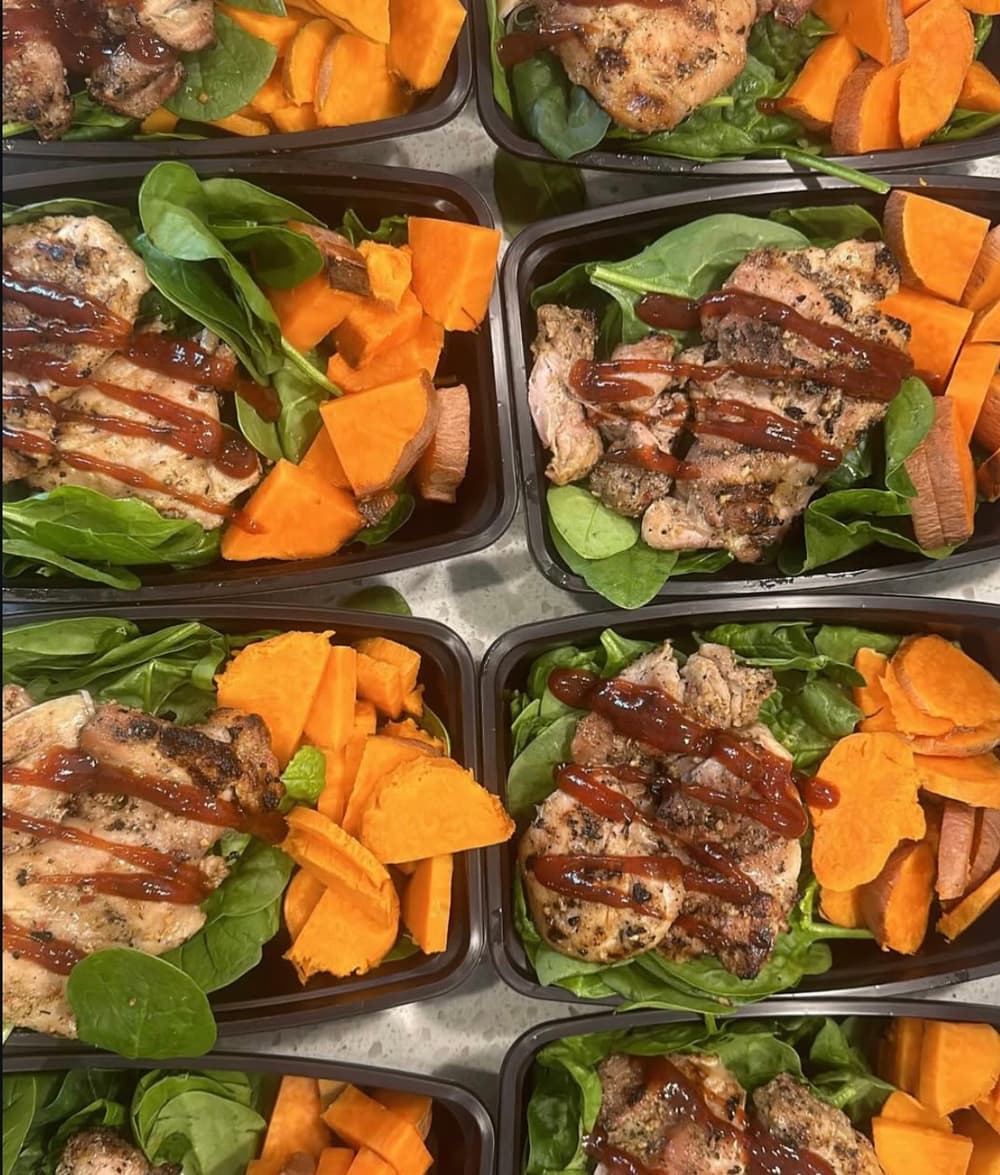 Overhead grid of containers with BBQ chicken, sweet potato and spinach